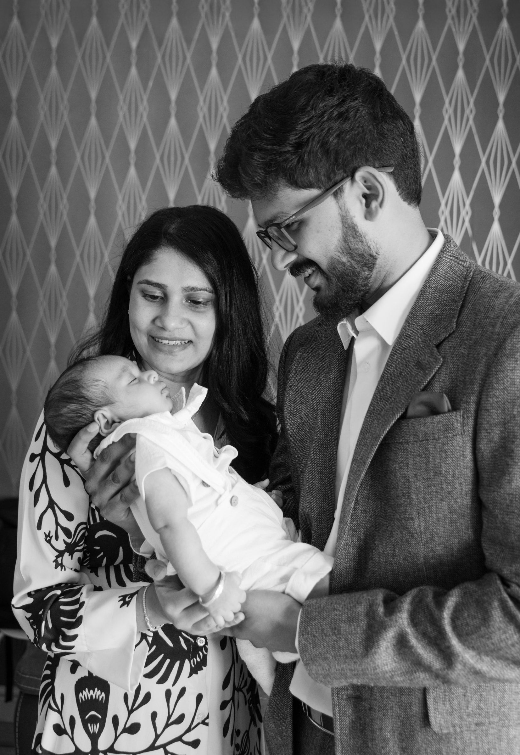Black-and-white portrait of parents holding their baby on a baptism day
