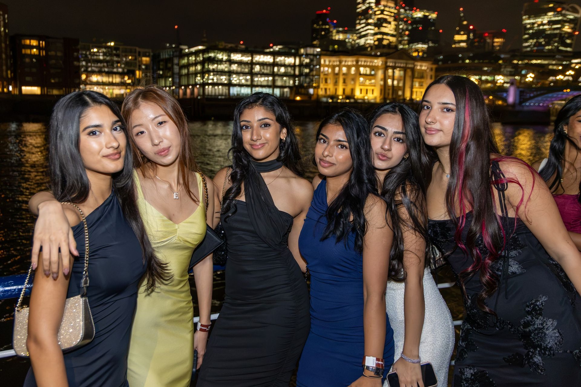 Friends in evening dress together on a boat beside the London skyline