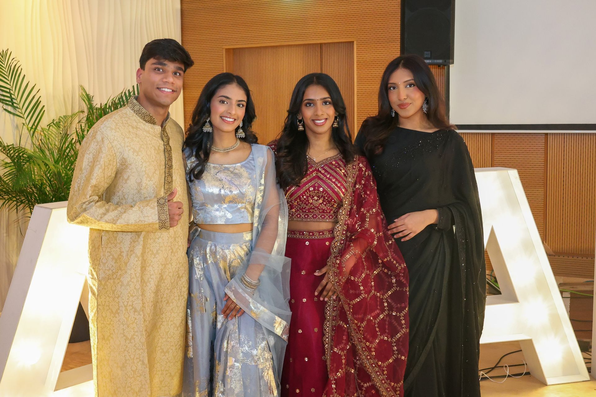 Four guests in colourful celebration outfits smiling together indoors