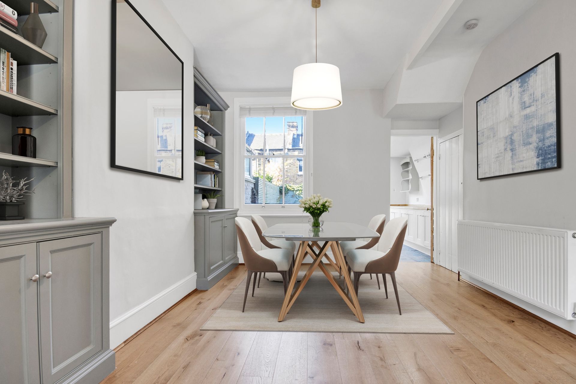 A light dining room with a round table, upholstered chairs and grey built-in cabinetry